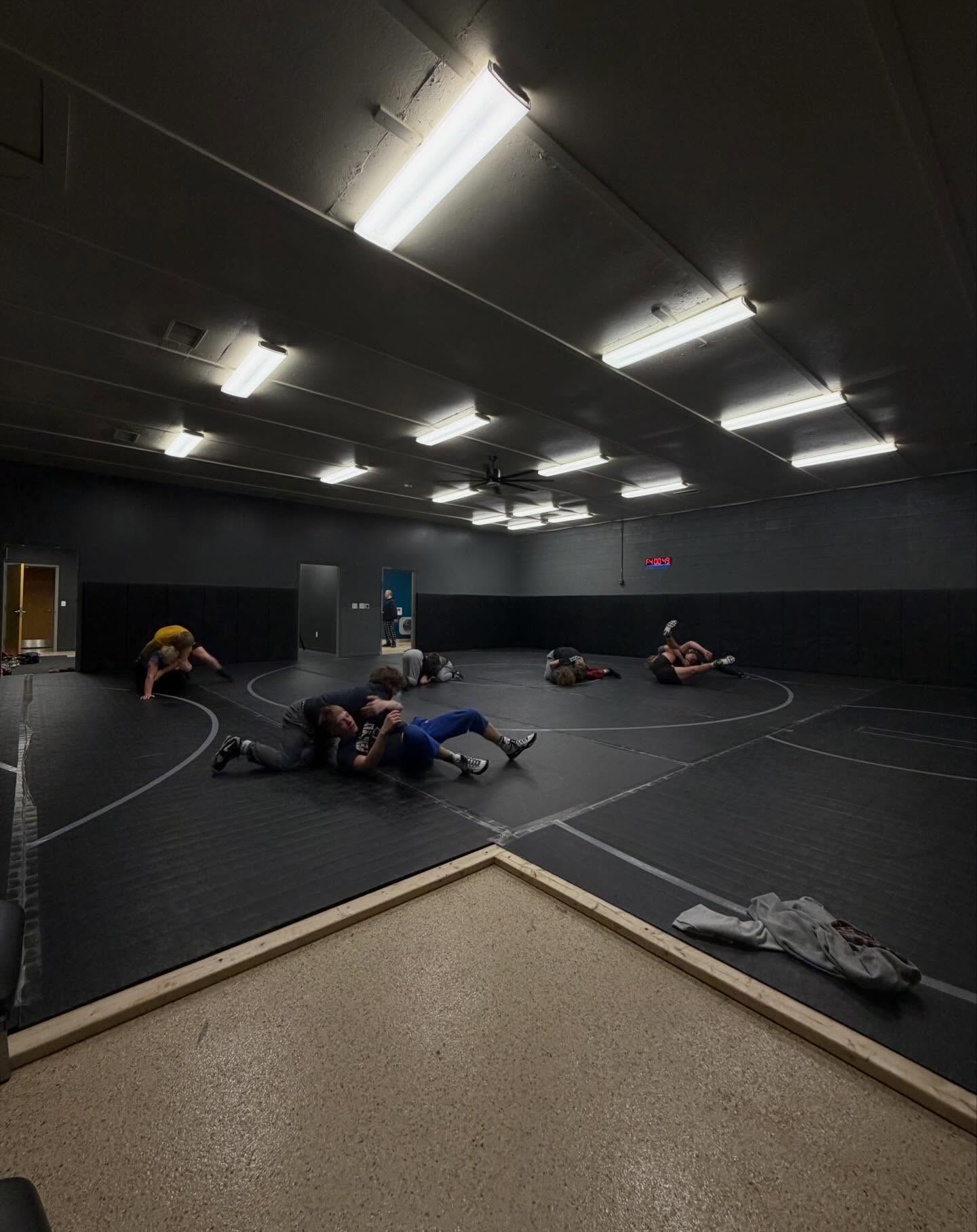 The Raw West wrestling room with athletes drilling in pairs on a full competition mat.