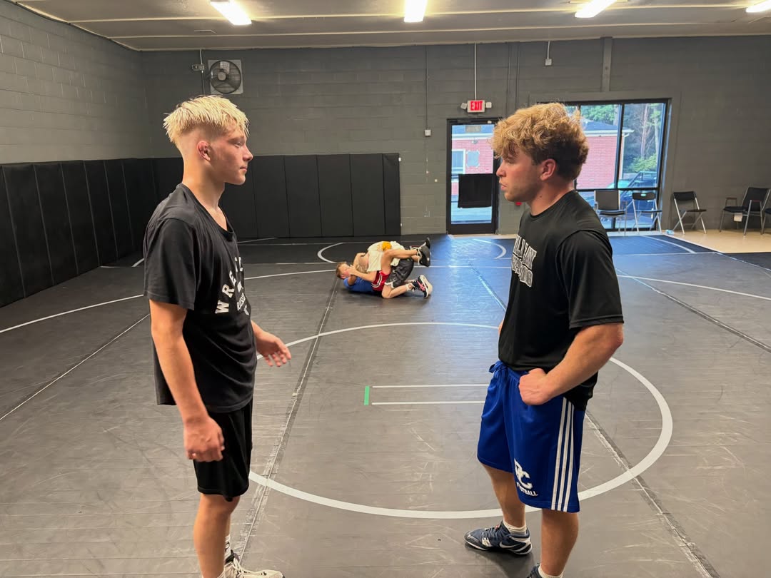 Two wrestlers squared up face to face while others work behind them.